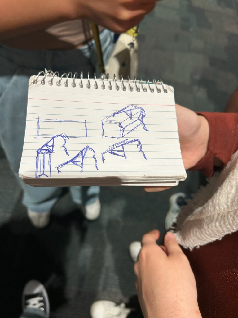 A designer showing a sketch of the blocks the competition uses.